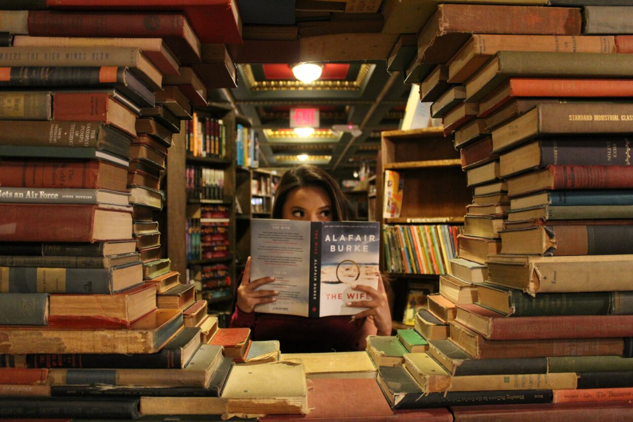 una persona con un libro rodeada de libros