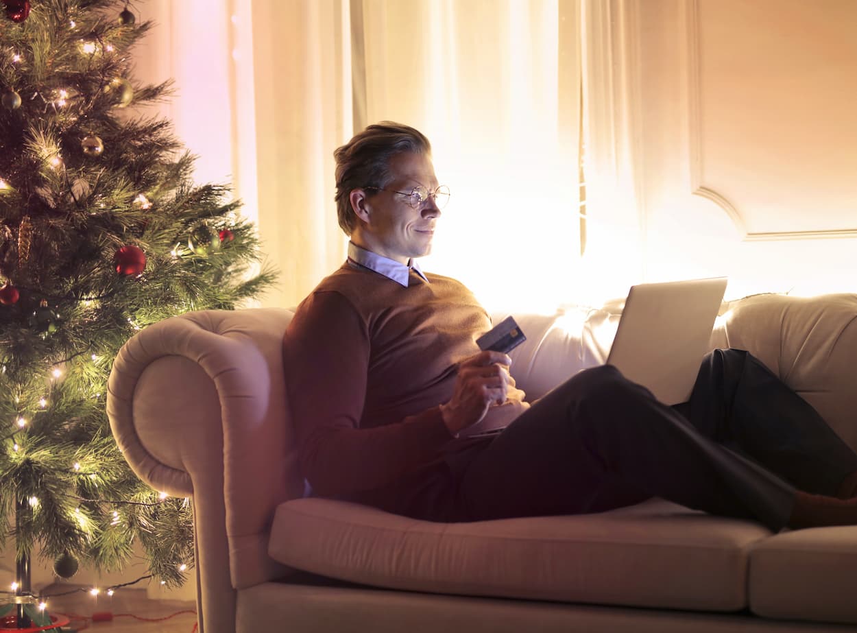 una persona sentada en su sofá junto a un árbol de navidad