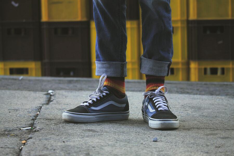 Una persona vestida con Vans Old Skool negras y azules.