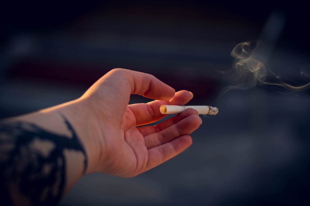La imagen muestra a alguien sosteniendo un cigarrillo encendido.