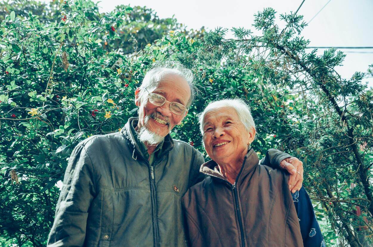 Una pareja de ancianos posando para una foto con una sonrisa en la cara. 