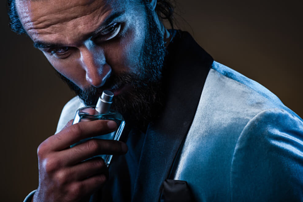 Una imagen que muestra a un hombre barbudo masculino sosteniendo una botella de perfume