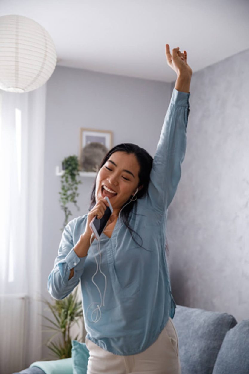 UN RETRATO DE UNA NIÑA QUE IMITA EL CANTO MIENTRAS ESCUCHA CANCIONES.