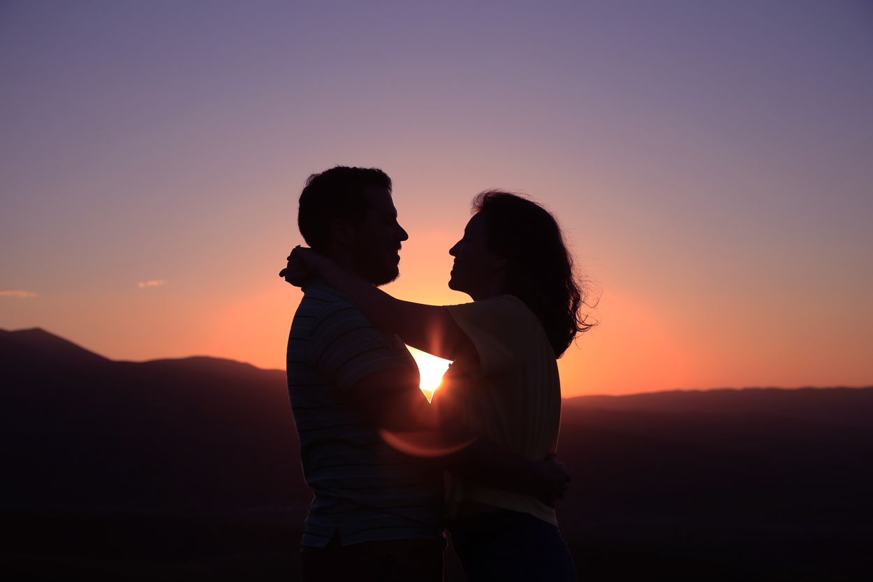 Dos personas frente a una puesta de sol.