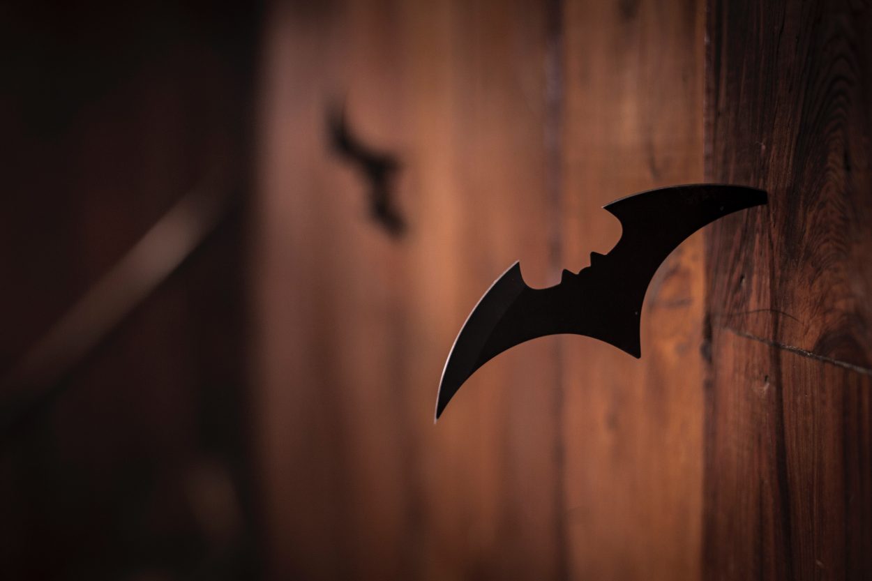 Un cuchillo arrojadizo con la forma del símbolo de Batman pegado a la pared.