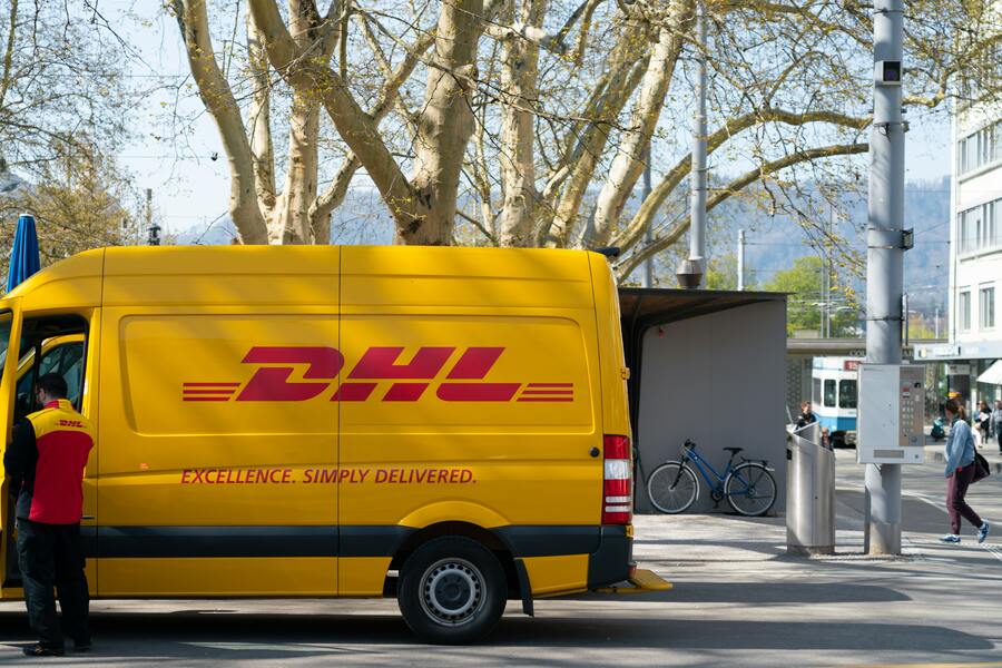 Un hombre parado frente a una furgoneta de reparto de DHL.