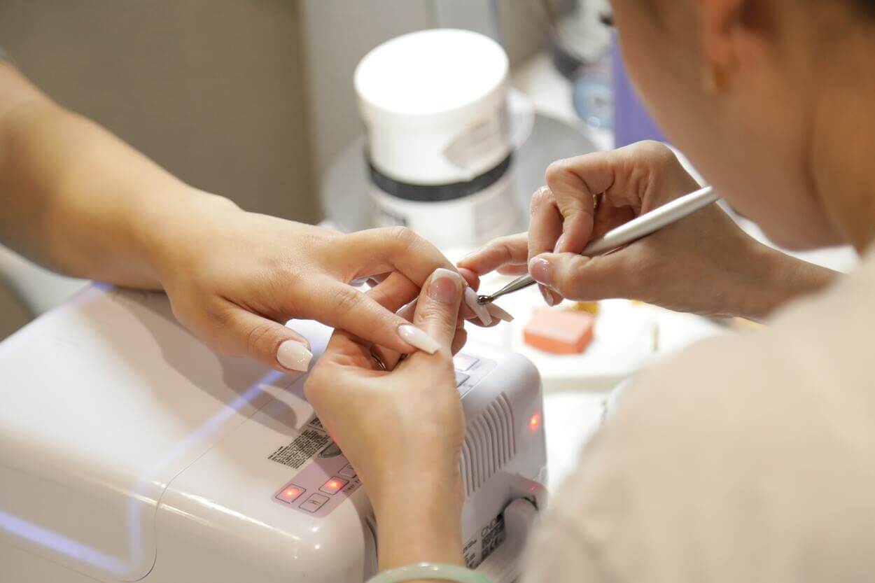 Una imagen de una mujer haciéndose las uñas en un salón.