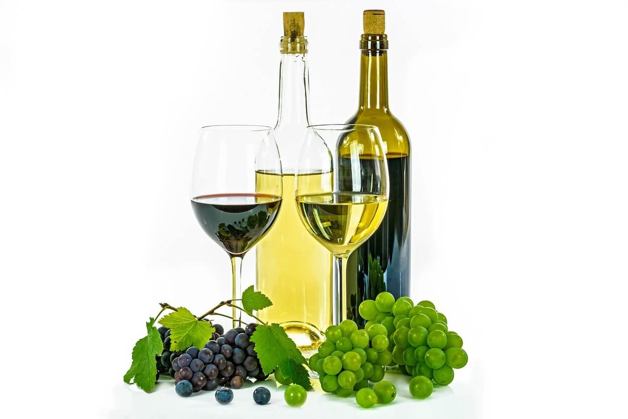 Una imagen de botellas de vino junto con copas y uvas.